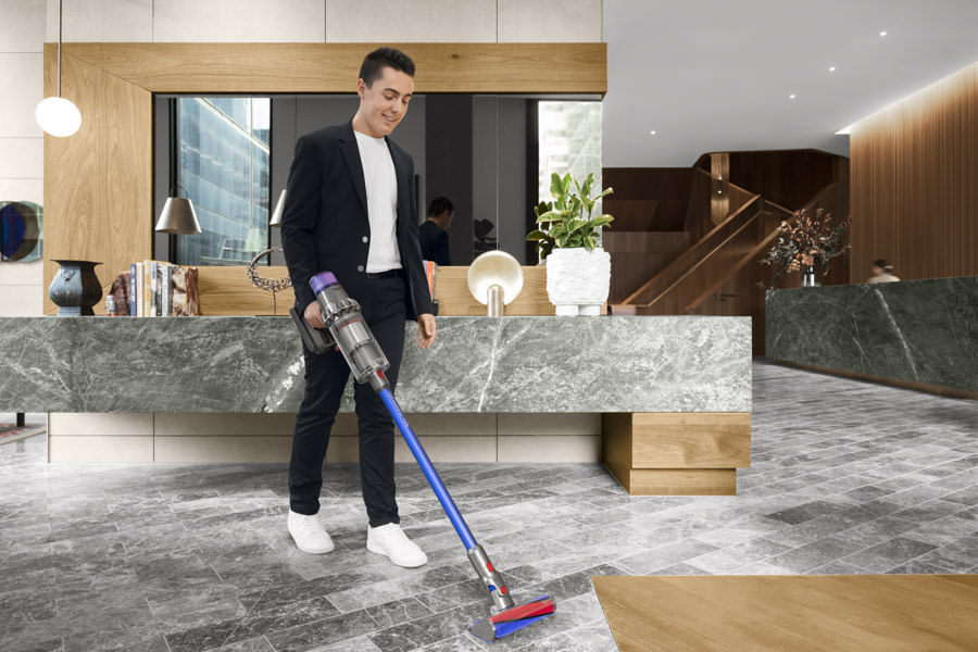 Product photography of a young man using a Dyson vacuum cleaner