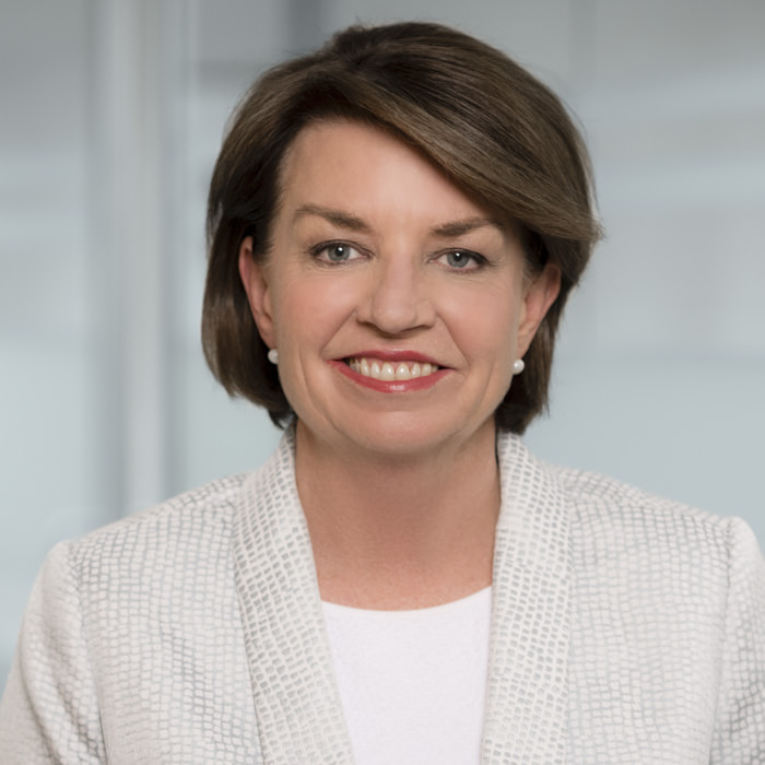Professional headshot photography of Anna Bligh, CEO of the Australian Banking Association A professional headshot of Anna Bligh, CEO of the Australian Banking Association and former premier of Queensland, wearing a textured white blazer and pearl earrings, in a modern Sydney office environment.
